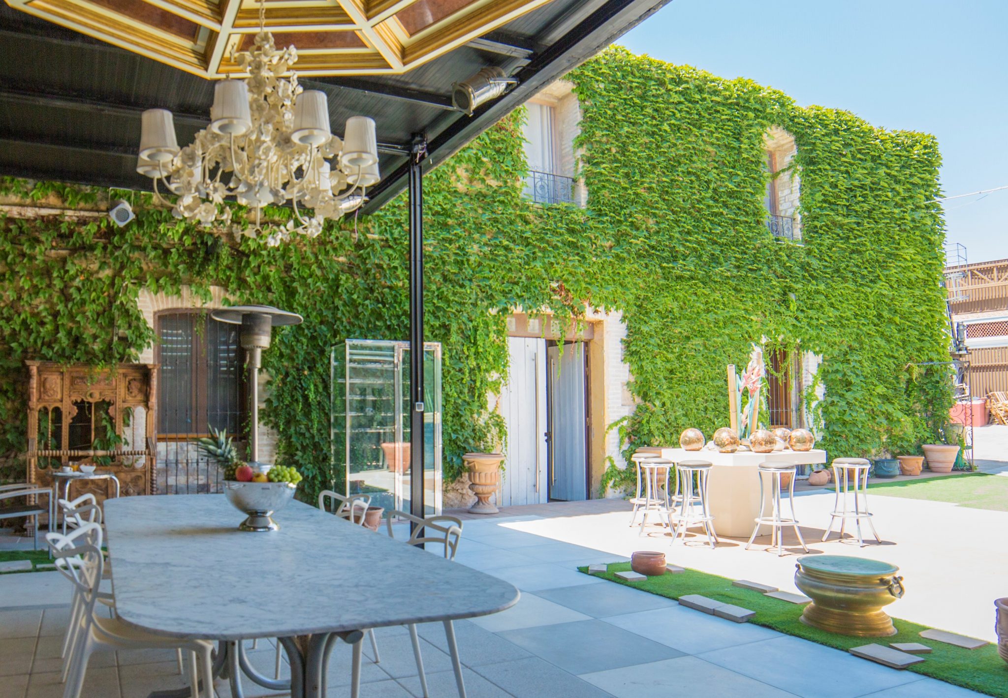 Patio cubierto en una gran mesa, sillas, una estufa y un muro que cubre completamente una planta colgante